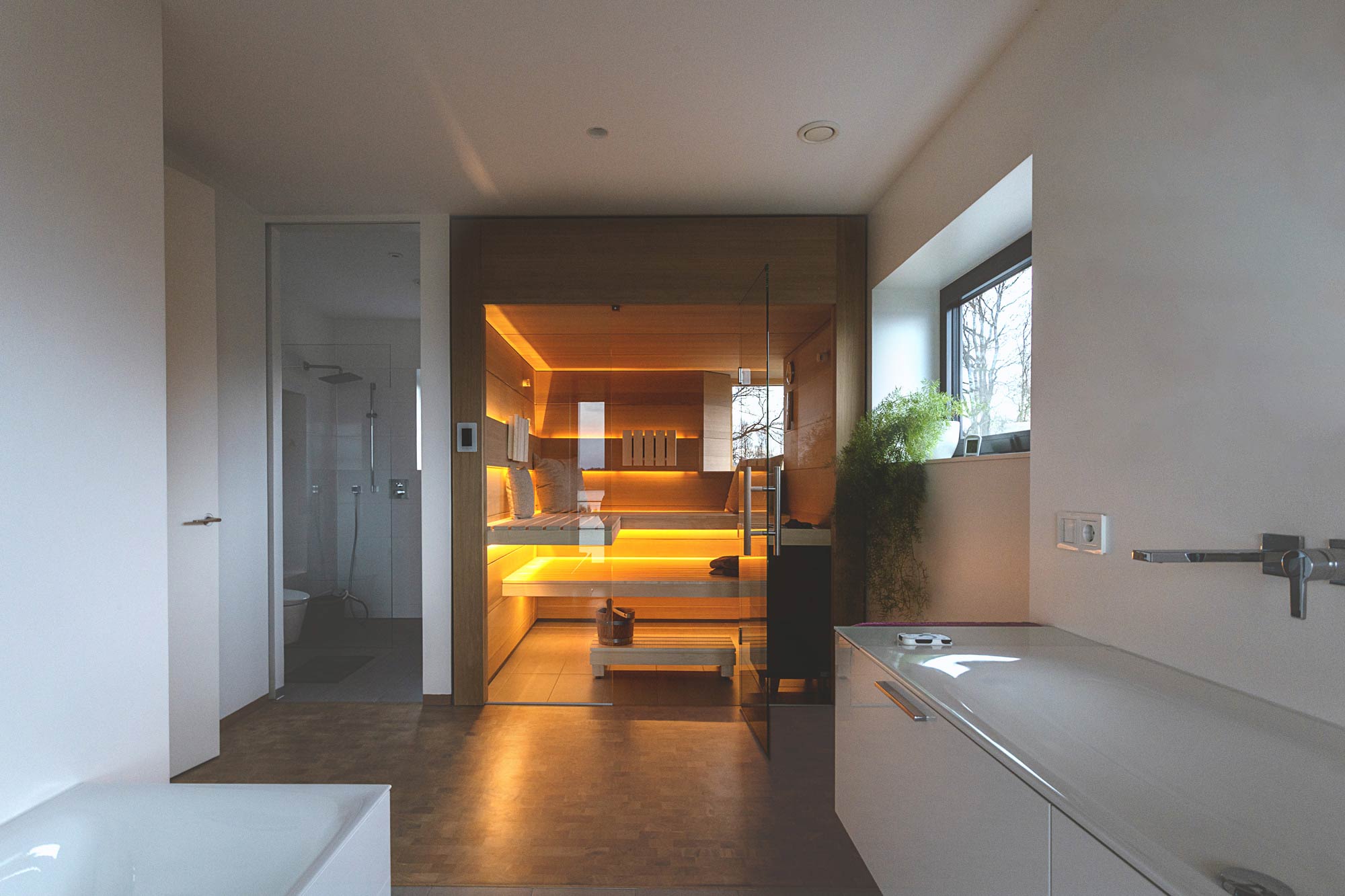 Moderne Sauna mit Glasfront und gelber Beleuchtung in Badezimmer